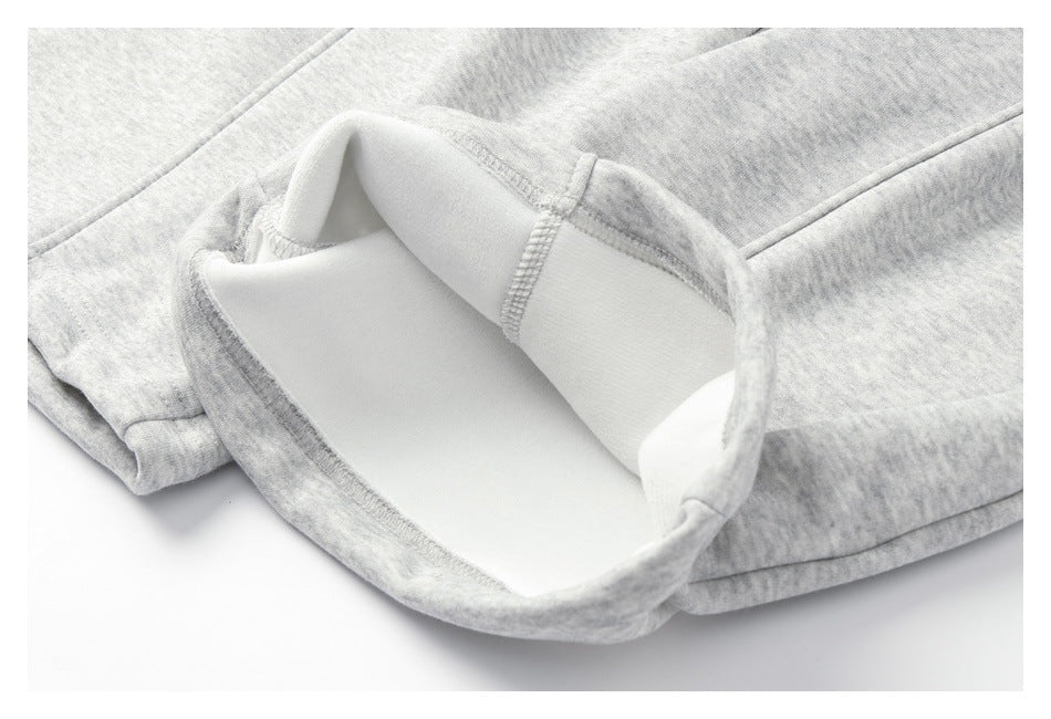 Close-up of a turned-back hem on light gray heathered sweatpants, showing the pale inner surface and stitching.