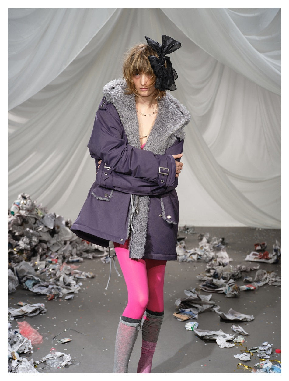 Model wearing a plum parka with a plush gray collar and buckle cuffs, crossed over the front.