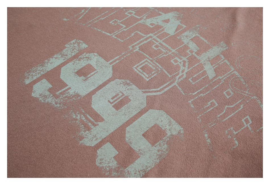 Close-up of dusty rose fabric printed with distressed pale mint numerals and geometric line art.