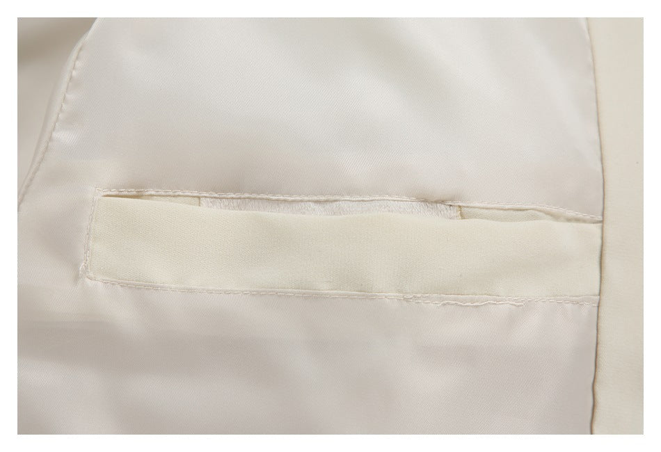 Close-up of a horizontal interior pocket opening and stitching on the cream jacket lining.