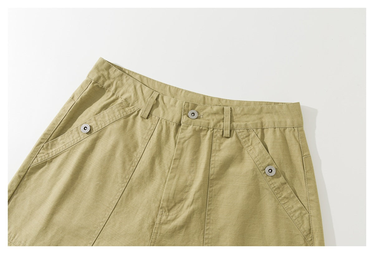 Close-up of khaki shorts showing the waistband, metal button, belt loops, and angled pocket openings.