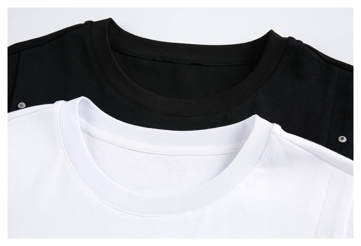 Close-up of black and white crew-neck T-shirts with small metal studs near the shoulders.