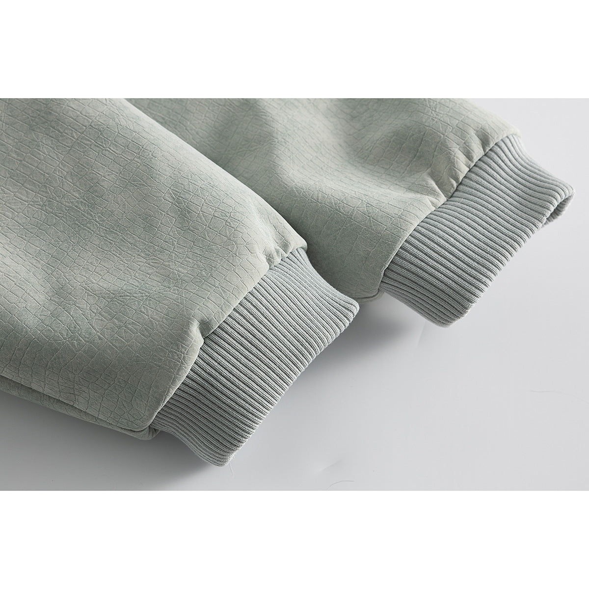 Close-up of the textured sage green jacket fabric and ribbed cuffs.