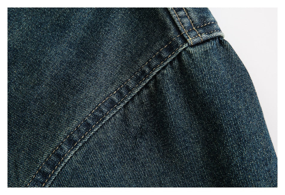 Close-up of a dark indigo denim shirt seam and stitched edge against a white background.