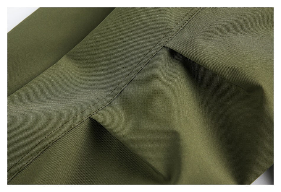 Close-up of olive garment fabric showing a stitched seam and gathered folds.