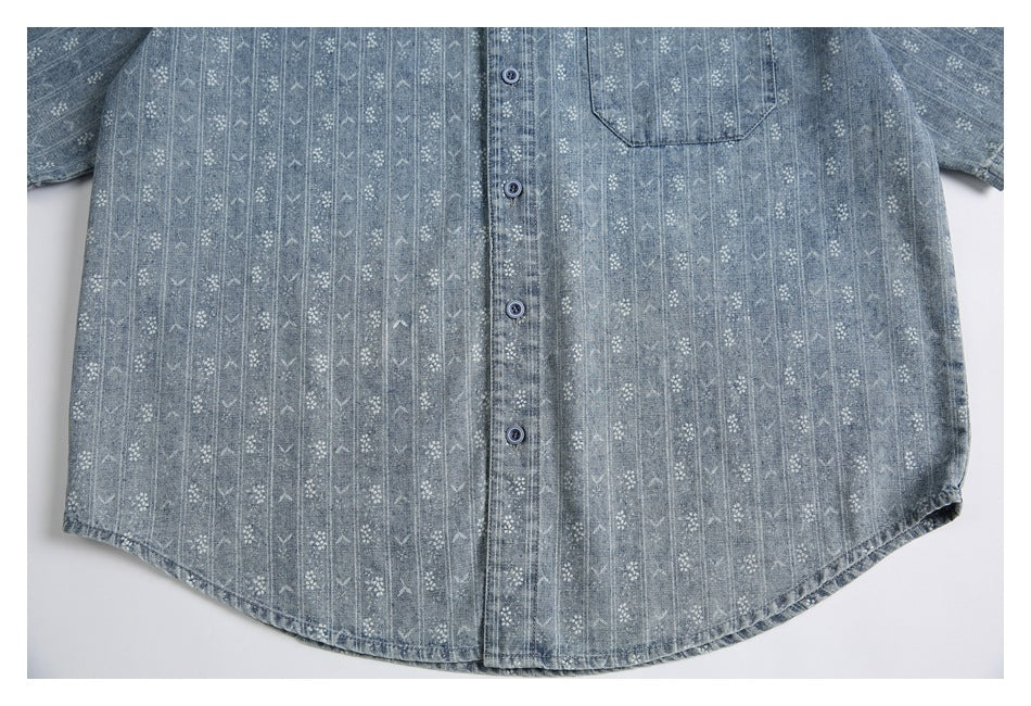 Cropped flat-lay view of the lower front of a blue-gray patterned button-up shirt, showing buttons and chest pocket.