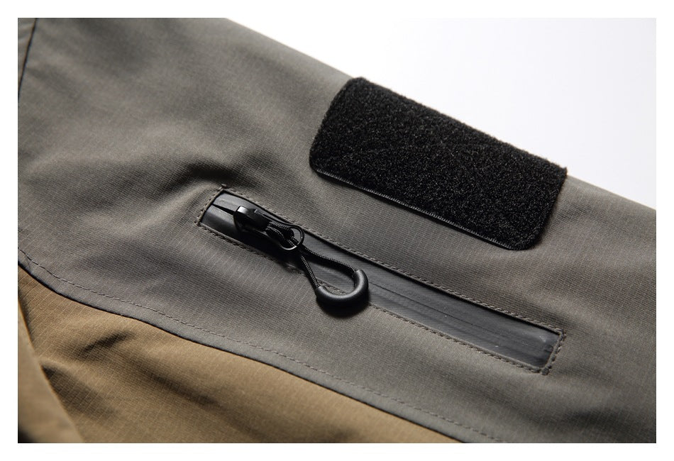 Close-up of a charcoal-gray jacket sleeve with a zip pocket and black hook-and-loop patch.
