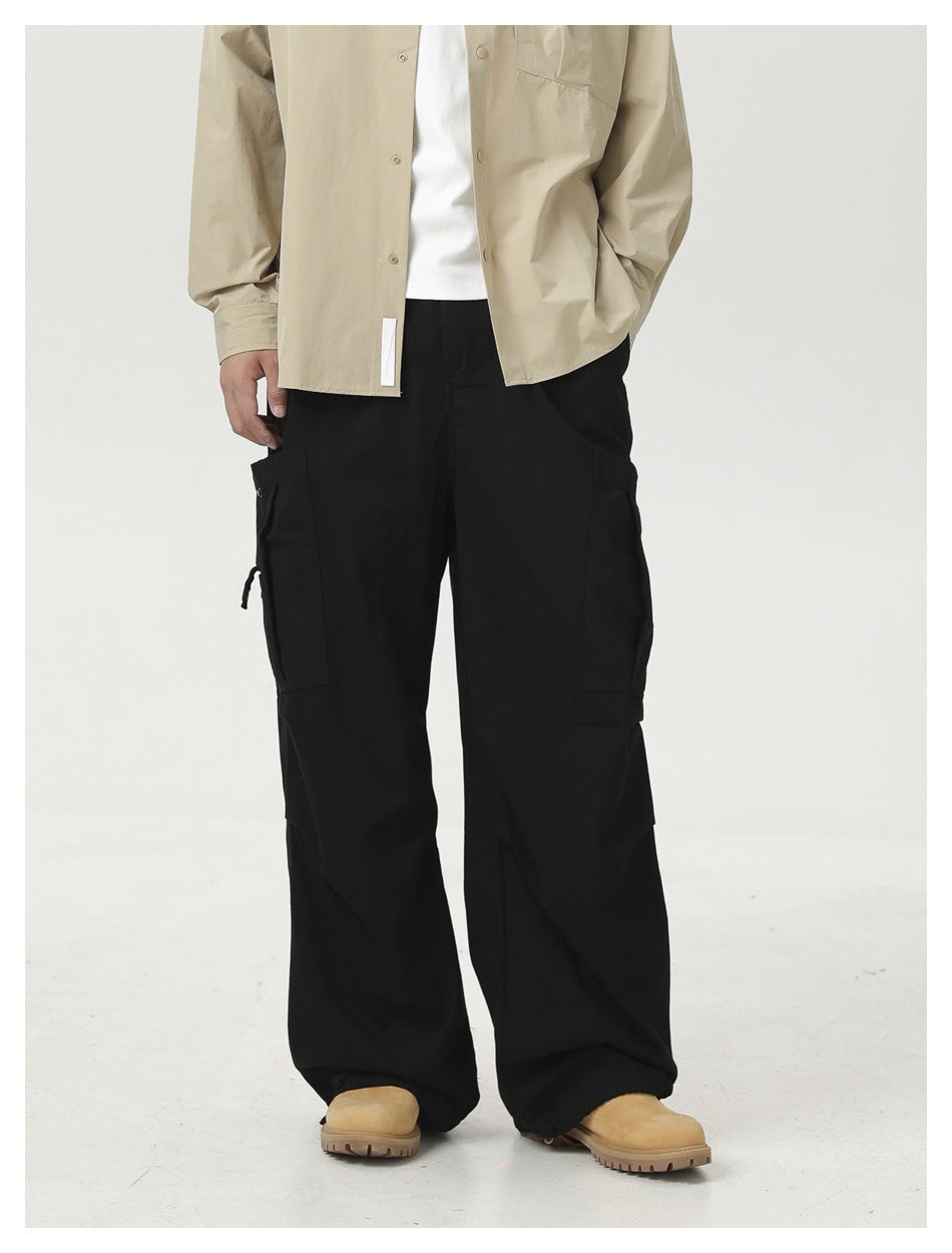 Close view of a model wearing black wide-leg cargo pants with side pockets, beige shirt and tan boots
