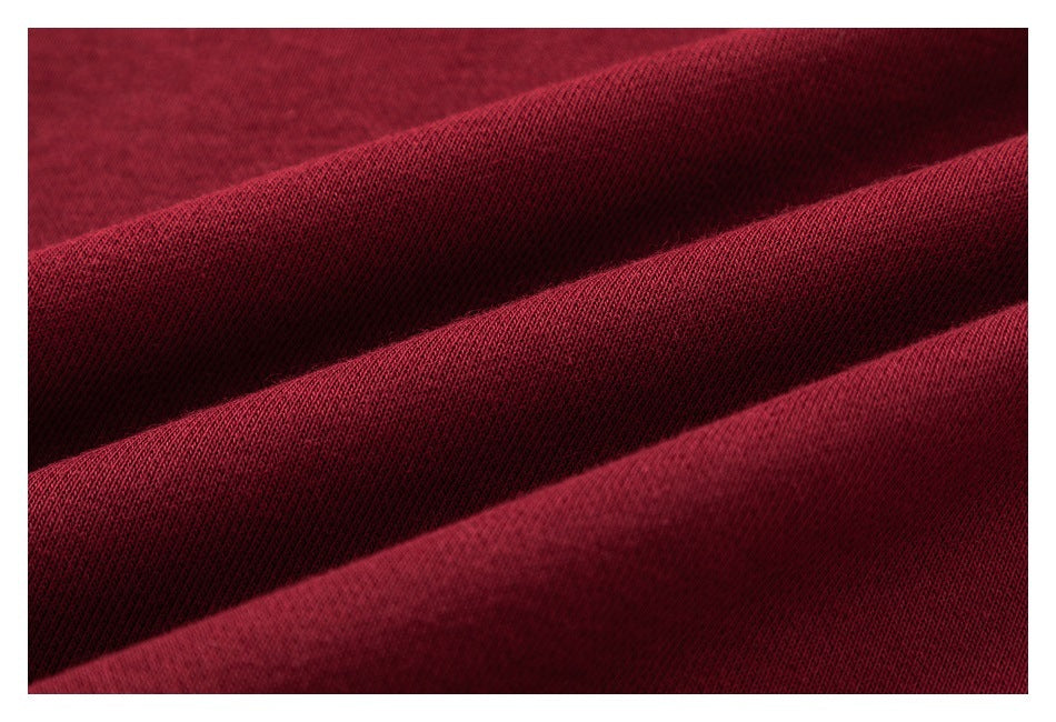 Macro view of burgundy fabric draped in folds, showing its fine knit texture.