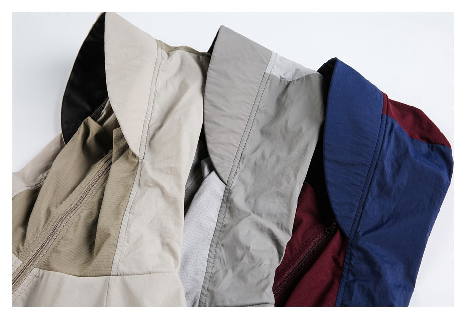 Close-up of overlapping hooded jackets in beige, gray, and navy with burgundy panels.