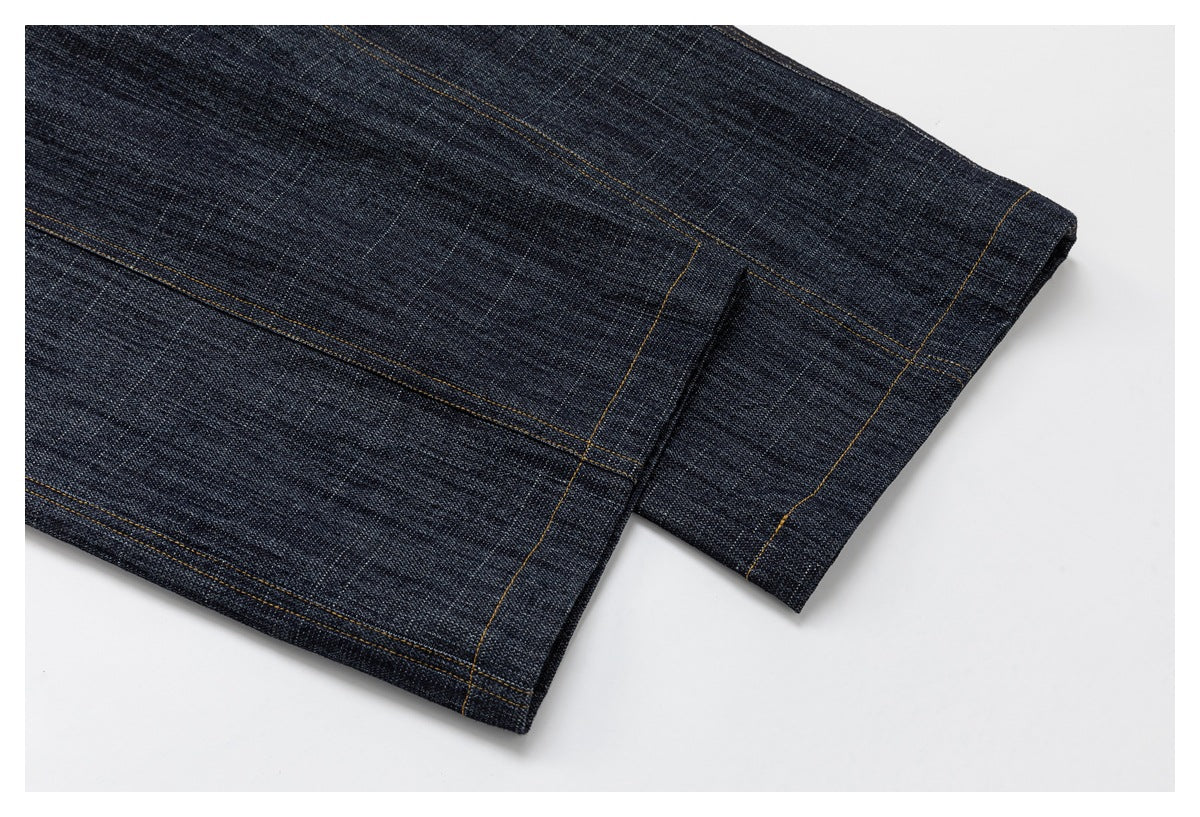 Close-up of dark indigo jeans showing a folded leg hem and golden stitching.