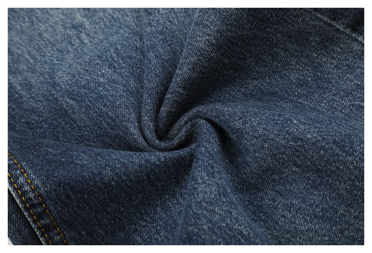 Close-up of dark blue denim fabric gathered to show its texture and weave.