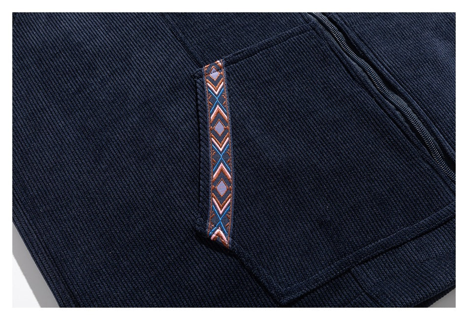 Close-up of a dark navy ribbed garment pocket with geometric-patterned trim and a nearby zipper.