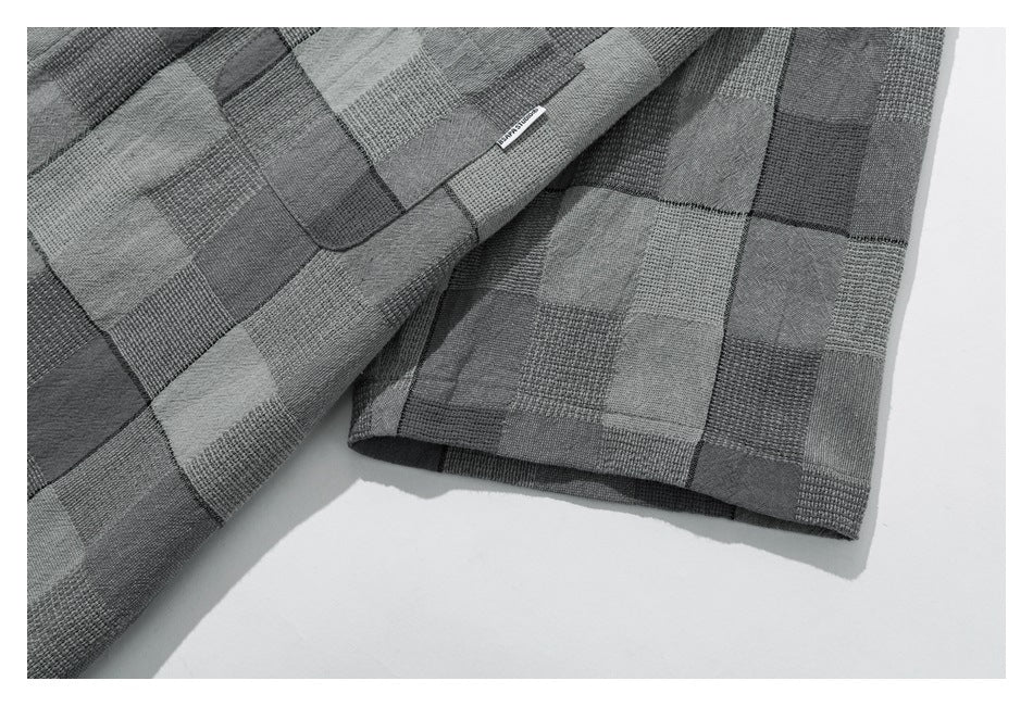 Close-up of the gray patchwork-check shirt’s short sleeve and stitched hem.