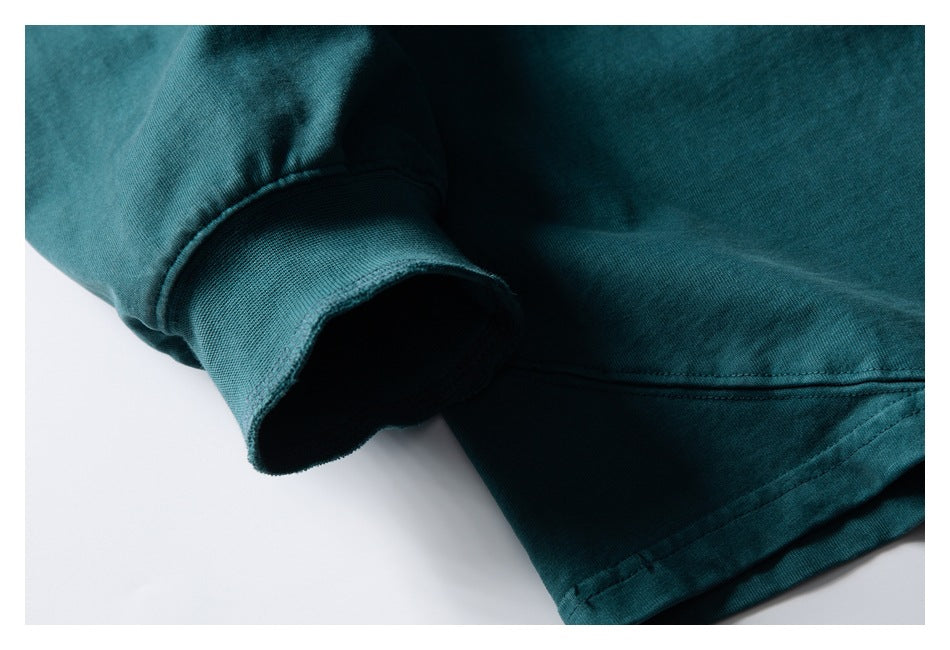 Close-up showing a dark teal sleeve cuff and the garment's stitched hem.