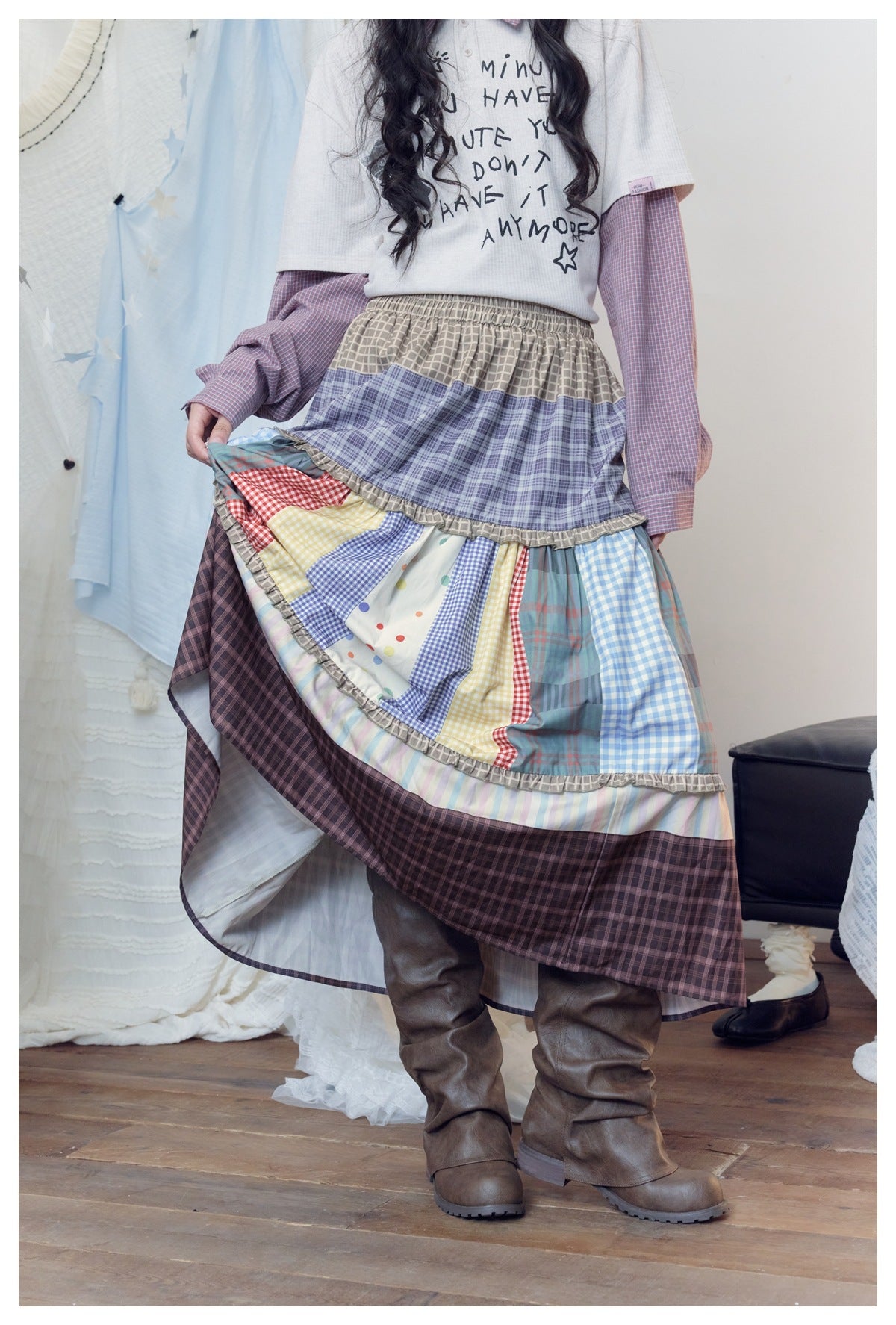 Model lifts the skirt to show its layered construction, colorful patchwork panels, ruffled seams, and pale lining.