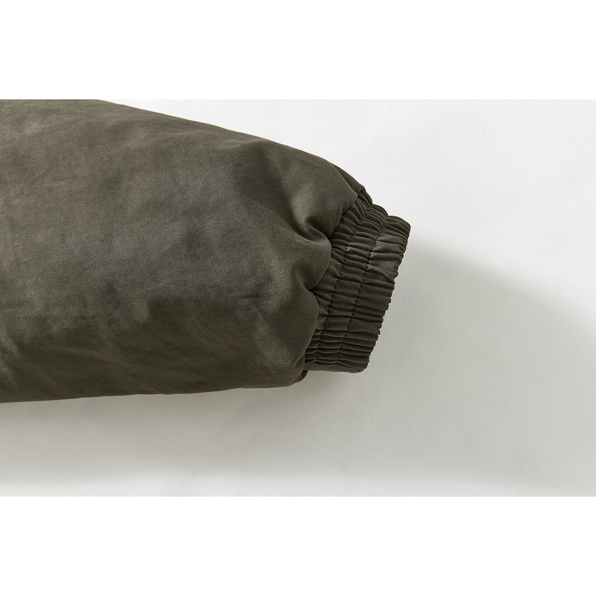 Close-up of an olive-gray jacket sleeve ending in a wide gathered elastic cuff.