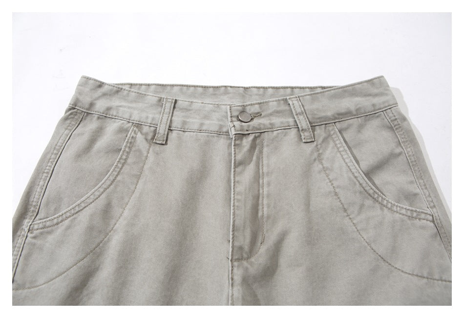 Close-up of light gray pants showing the waistband, button closure, belt loops, and curved front pockets.