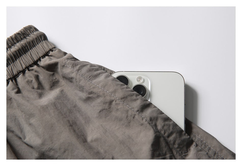 Close-up of the charcoal-gray shorts' elastic waistband and pocket holding a white smartphone.