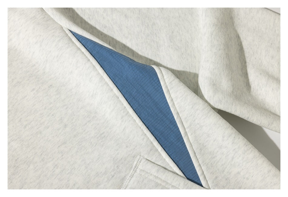 Close-up of a light heather-gray garment with a blue inset panel and visible seam details.