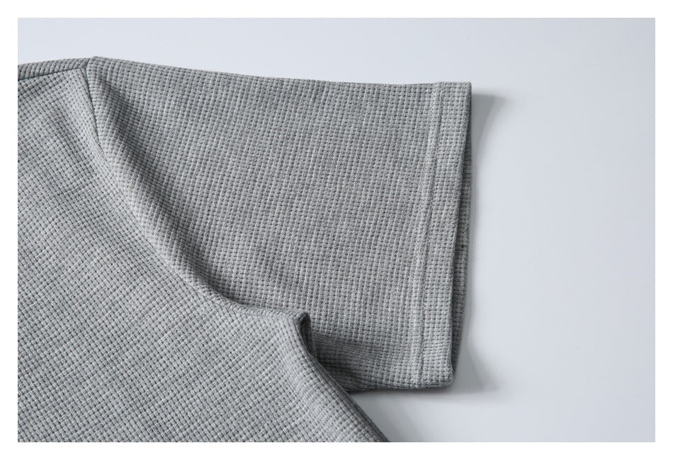 Close-up of a gray textured garment sleeve and stitched cuff.
