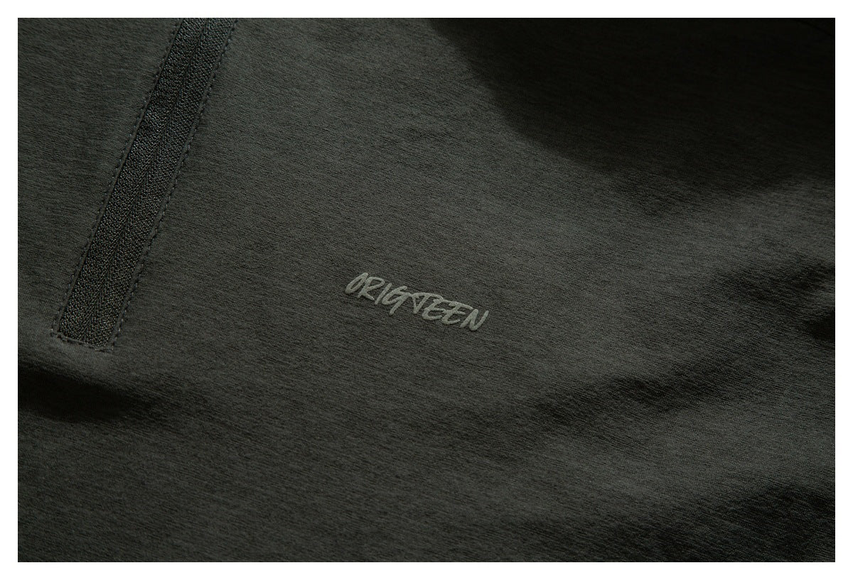 Close-up of dark charcoal fabric with a small light-colored logo and a narrow zipper.