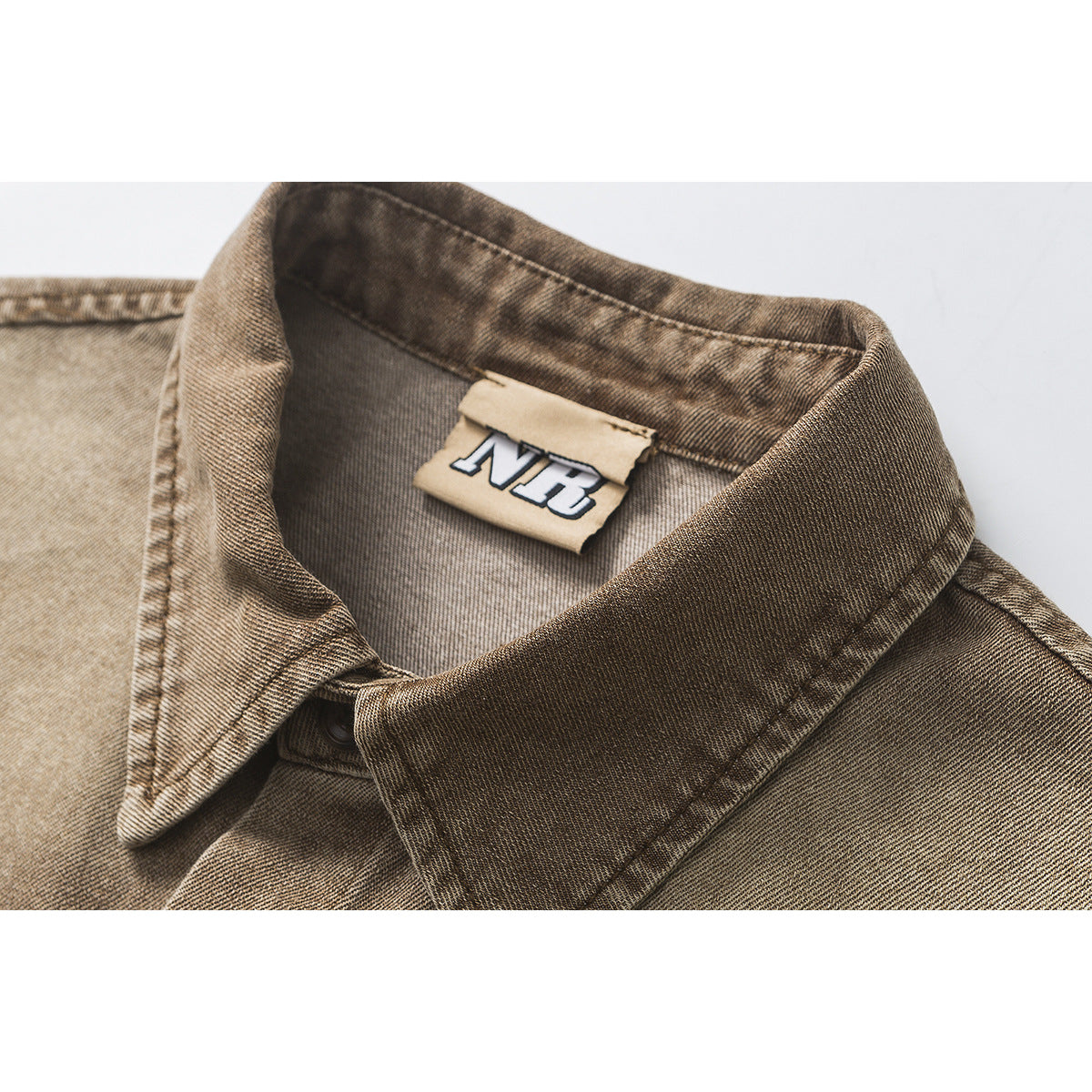 Close-up of a brown washed button-up shirt collar and neck label.
