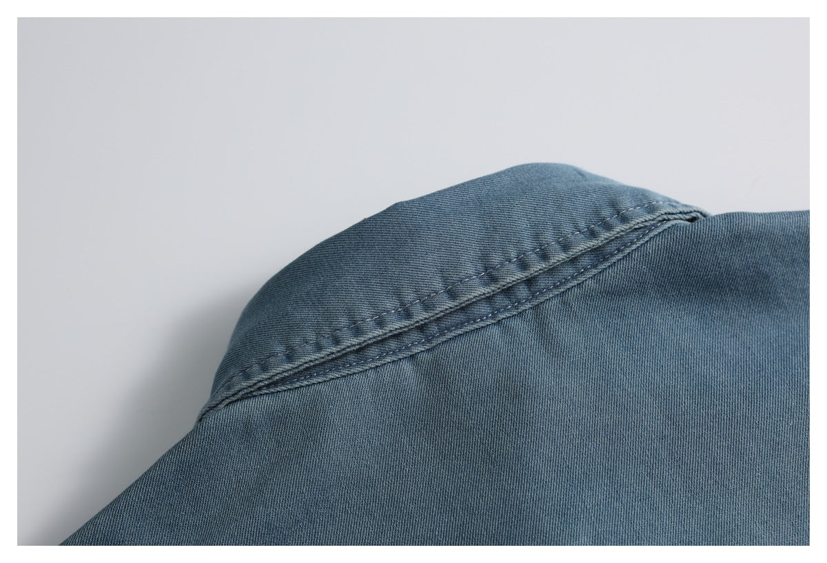 Close-up of a blue denim shirt shoulder seam with double stitching.