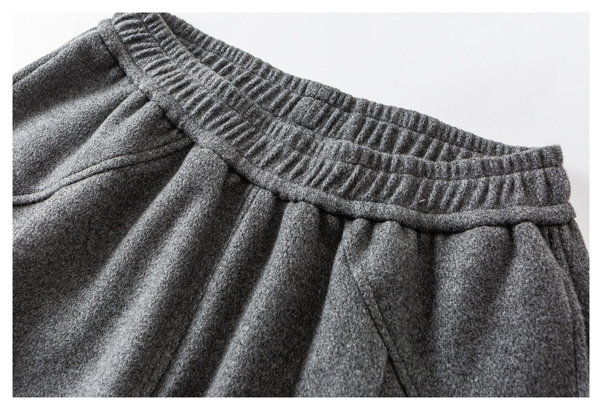 Close-up of charcoal gray trousers showing the gathered elastic waistband and front pleats.