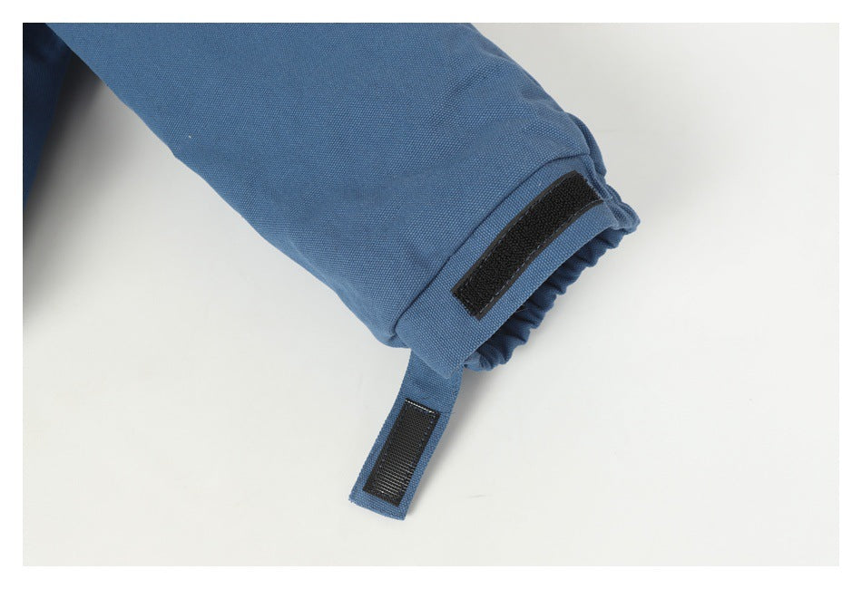 Close-up of a blue jacket sleeve cuff with a black hook-and-loop adjustment strap.