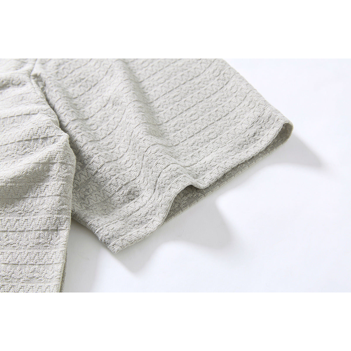 Close-up of the short sleeve and textured striped fabric of a light gray shirt.