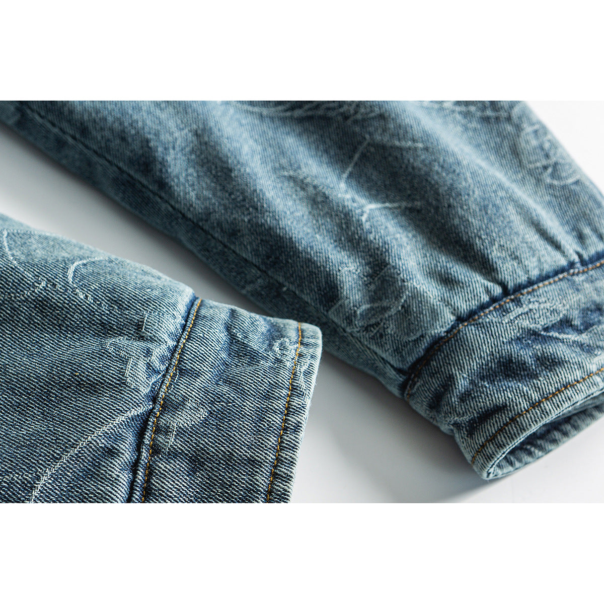Close-up of two blue denim jacket sleeves showing the cuffs, seams, and faded finish.