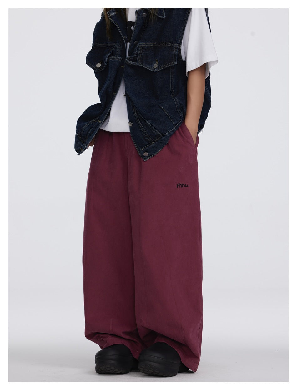 Angled view of a model wearing burgundy wide-leg pants with a dark denim vest and white T-shirt.
