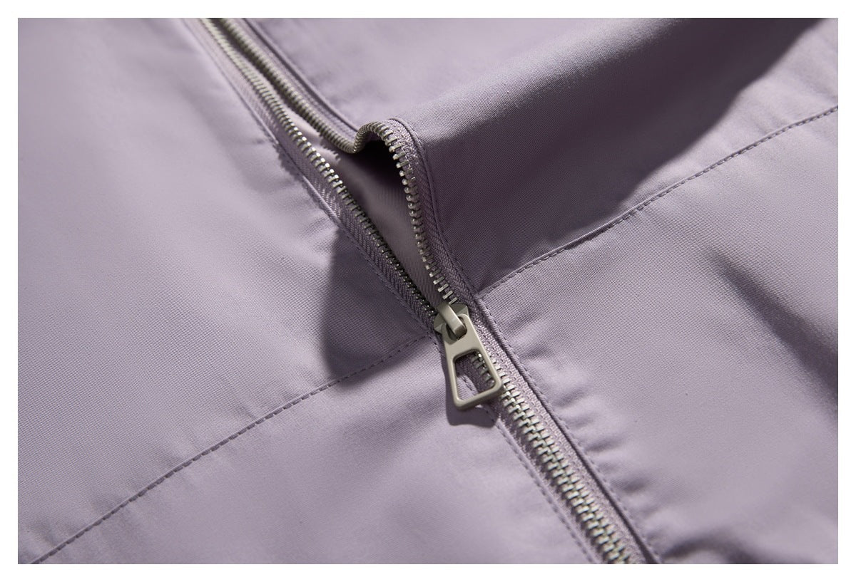 Close-up of a metal zipper and stitched seam on a lavender-gray garment.