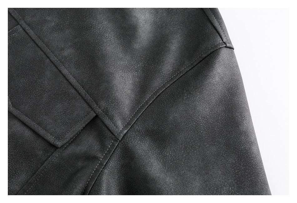 Close-up of a dark jacket showing a textured surface, curved seams, and part of a flap pocket.