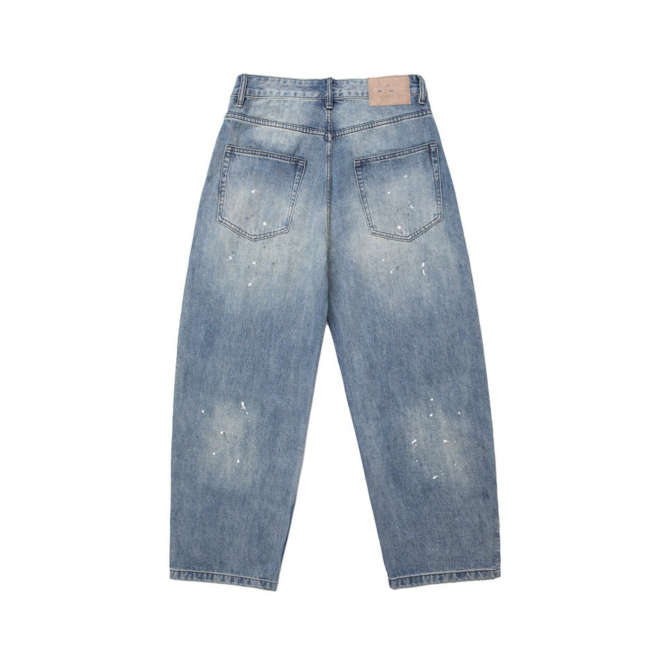 Back of light blue washed jeans with two patch pockets, white paint splatter and a tan waistband patch