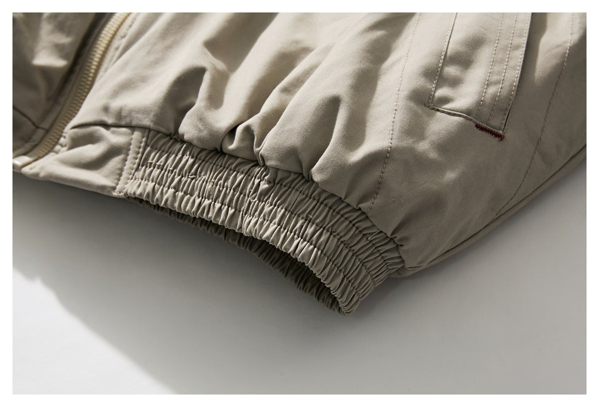 Close-up of the beige jacket's gathered elastic hem and welt pocket.