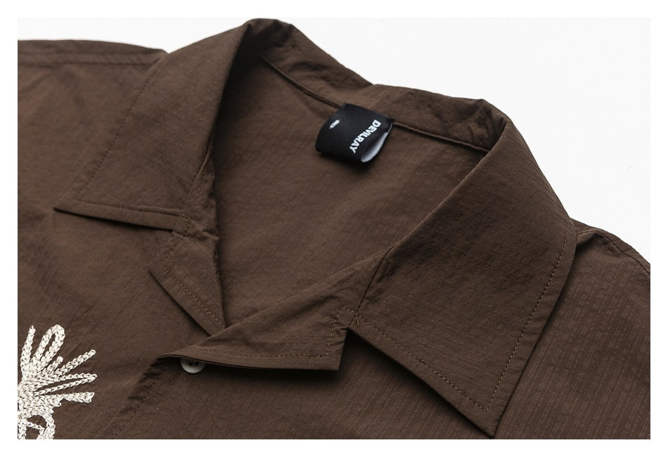 Close-up of the dark brown shirt's pointed collar, seam details, and neck label.