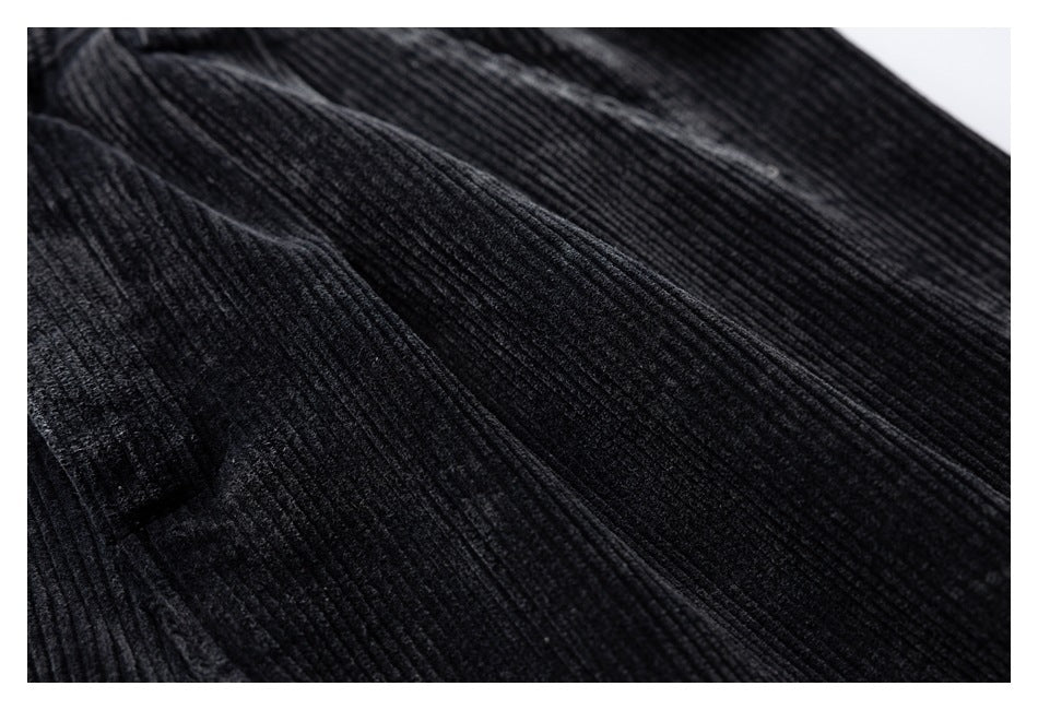 Close-up showing the ribbed texture and stitching of black corduroy trousers.