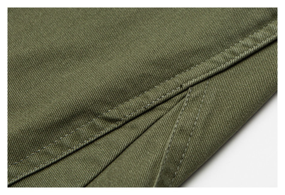 Close-up of olive-green trouser fabric with a folded, stitched seam.