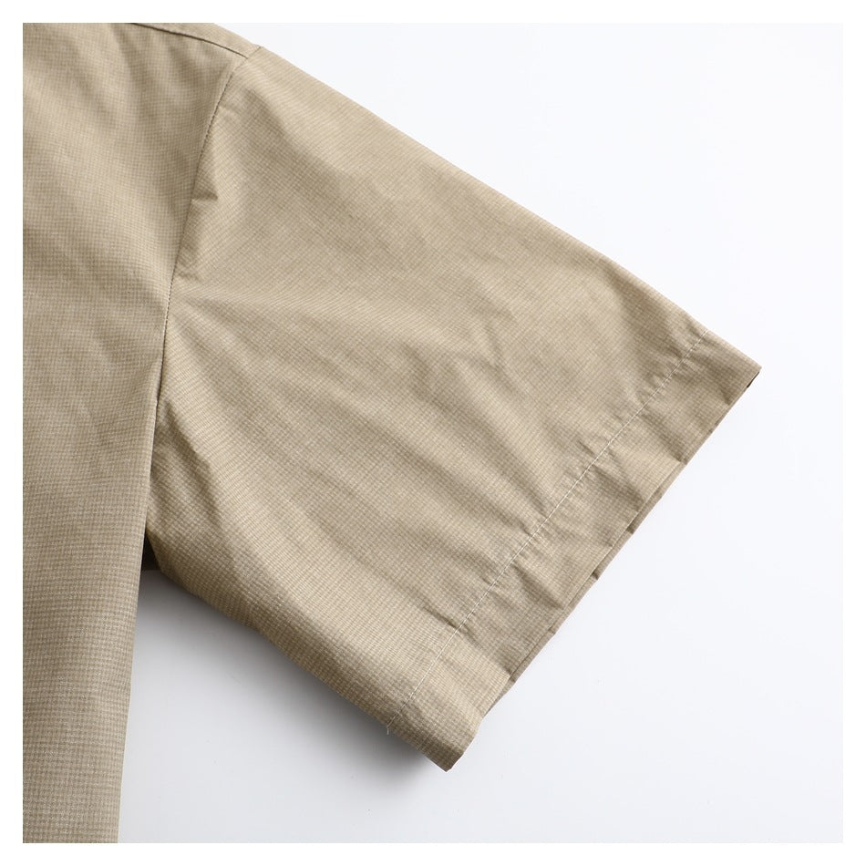 Close-up of the short sleeve and stitched cuff of a beige micro-check shirt.