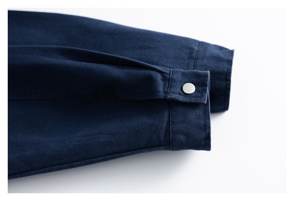 Close-up of a navy jacket sleeve cuff with a fastening tab and silver snap.