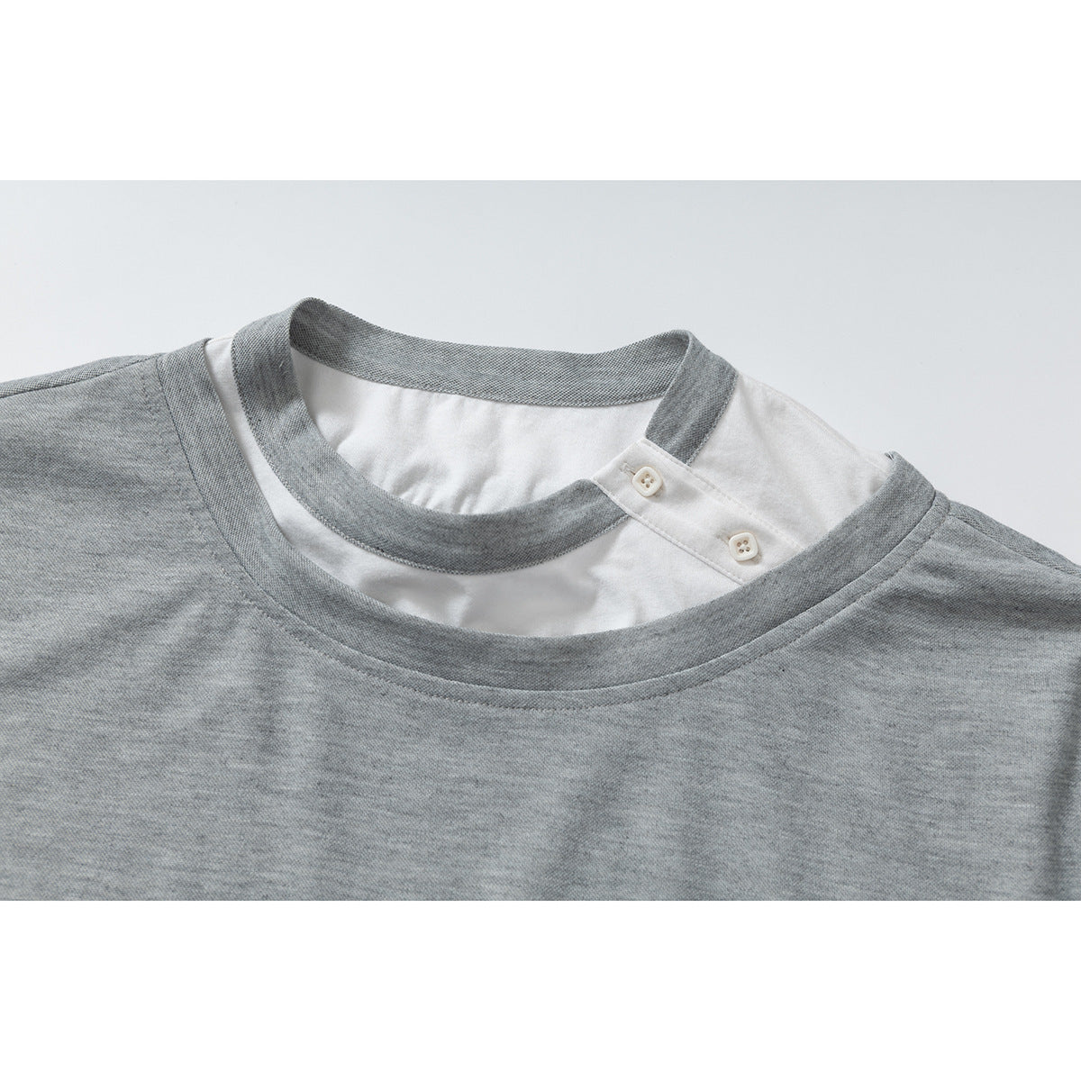 Close-up of a gray T-shirt neckline with a white inset collar and two small buttons.