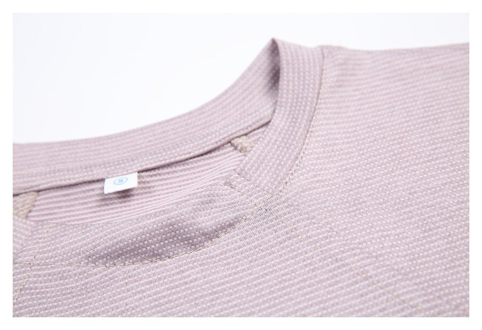 Close-up of the pale mauve shirt's crew-neck stitching, inner tag, and patterned fabric.