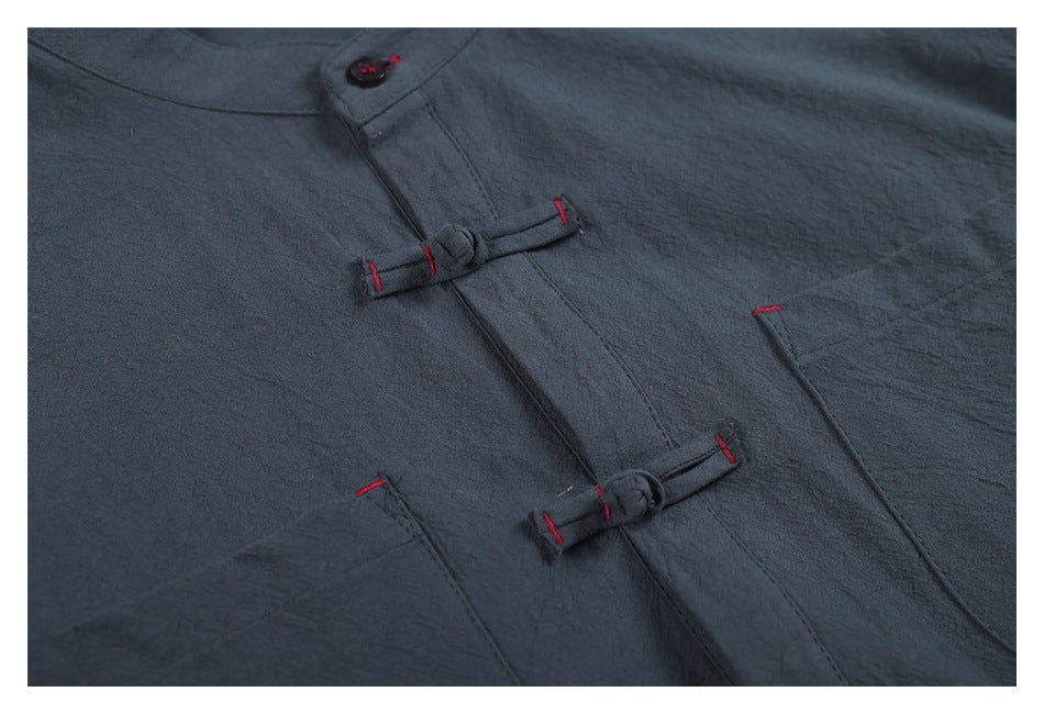 Close-up of a charcoal-blue garment front with a button and two loop closures accented by red stitching.