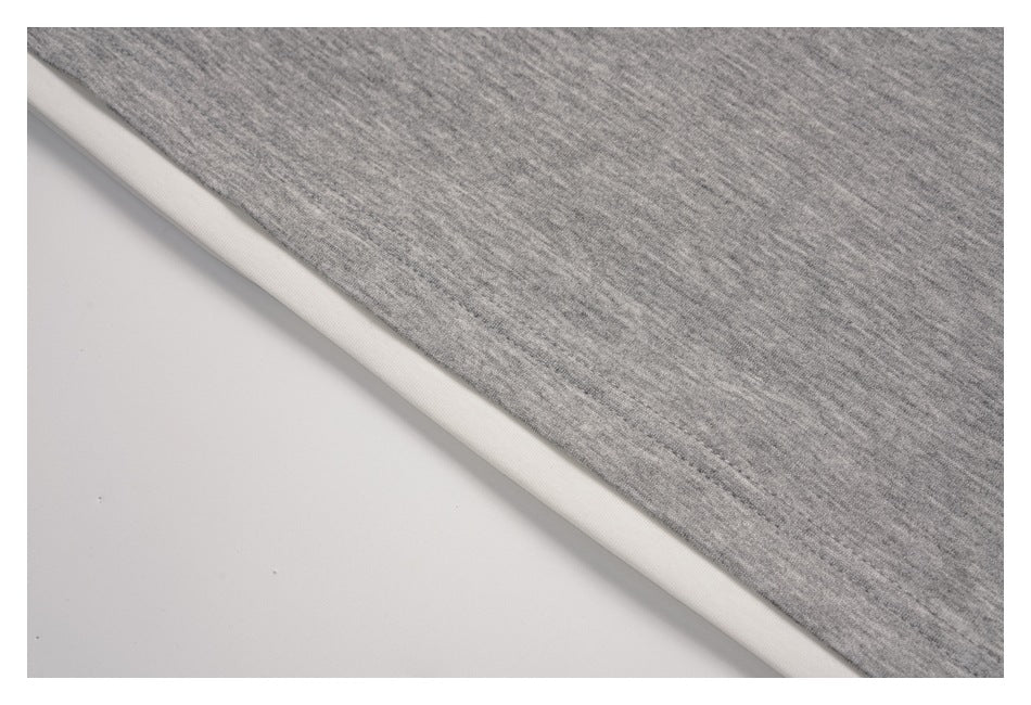 Close-up of the gray pullover's hem with a white layer visible underneath.