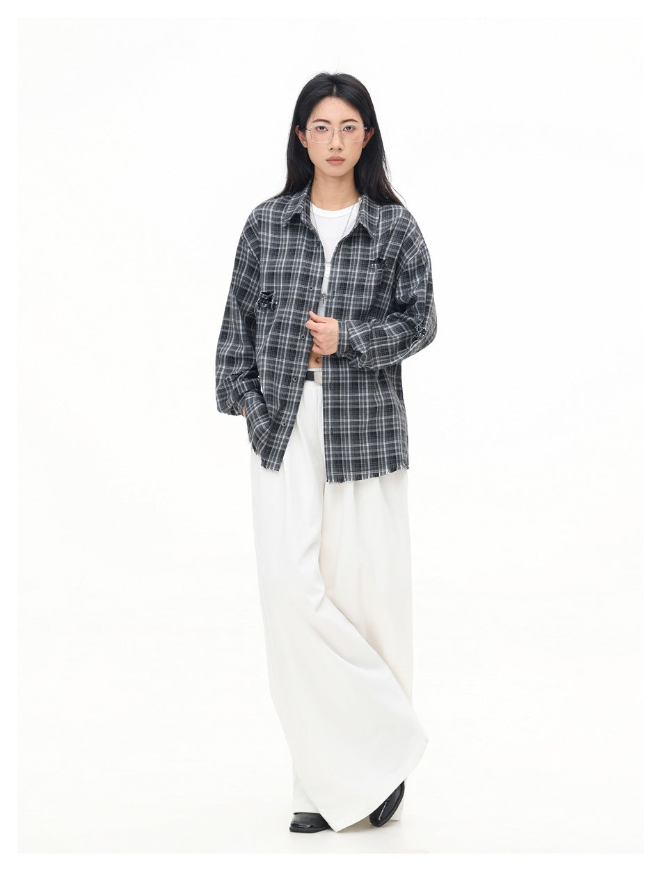 Full-length model wearing a charcoal gray plaid button-up shirt with distressed details and white wide-leg trousers.