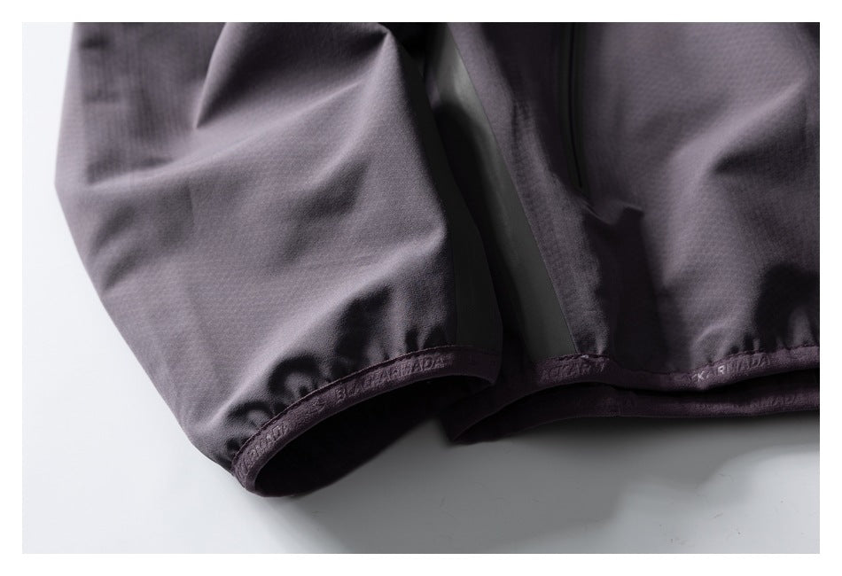Close-up of the charcoal-gray pullover’s gathered cuff and hem, with subtle embossed lettering.
