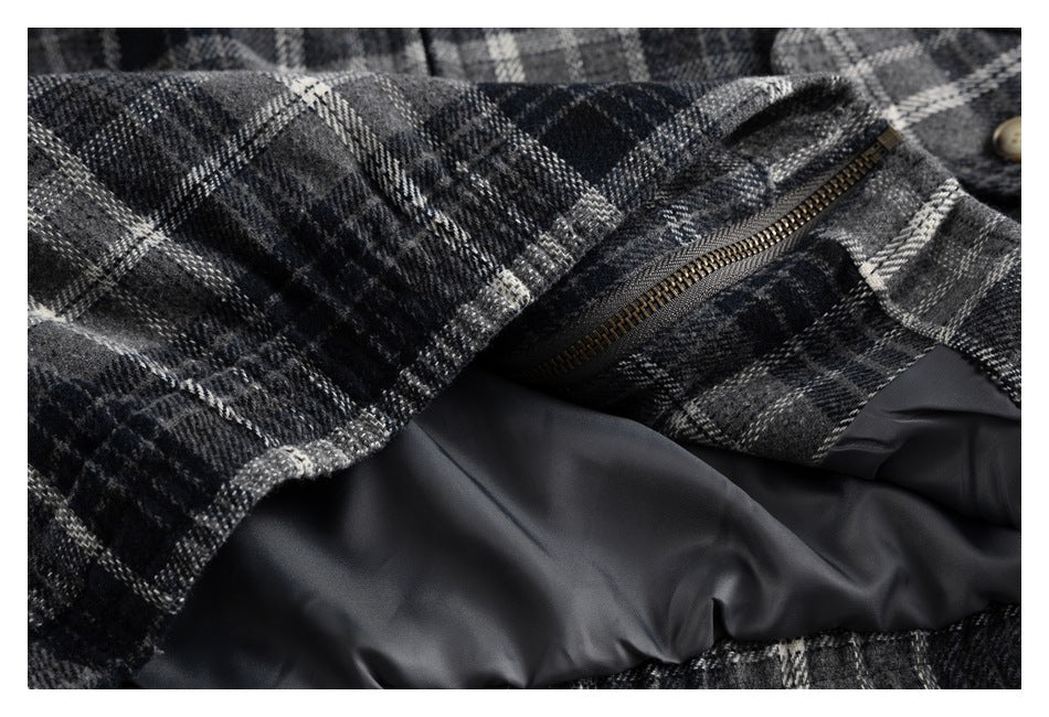 Close-up of a black, gray, and white plaid garment showing a bronze zipper and smooth dark lining.