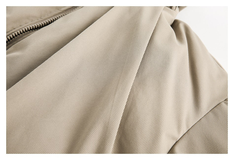 Close-up of the beige jacket's ribbed fabric, front panel, and diagonal seam.